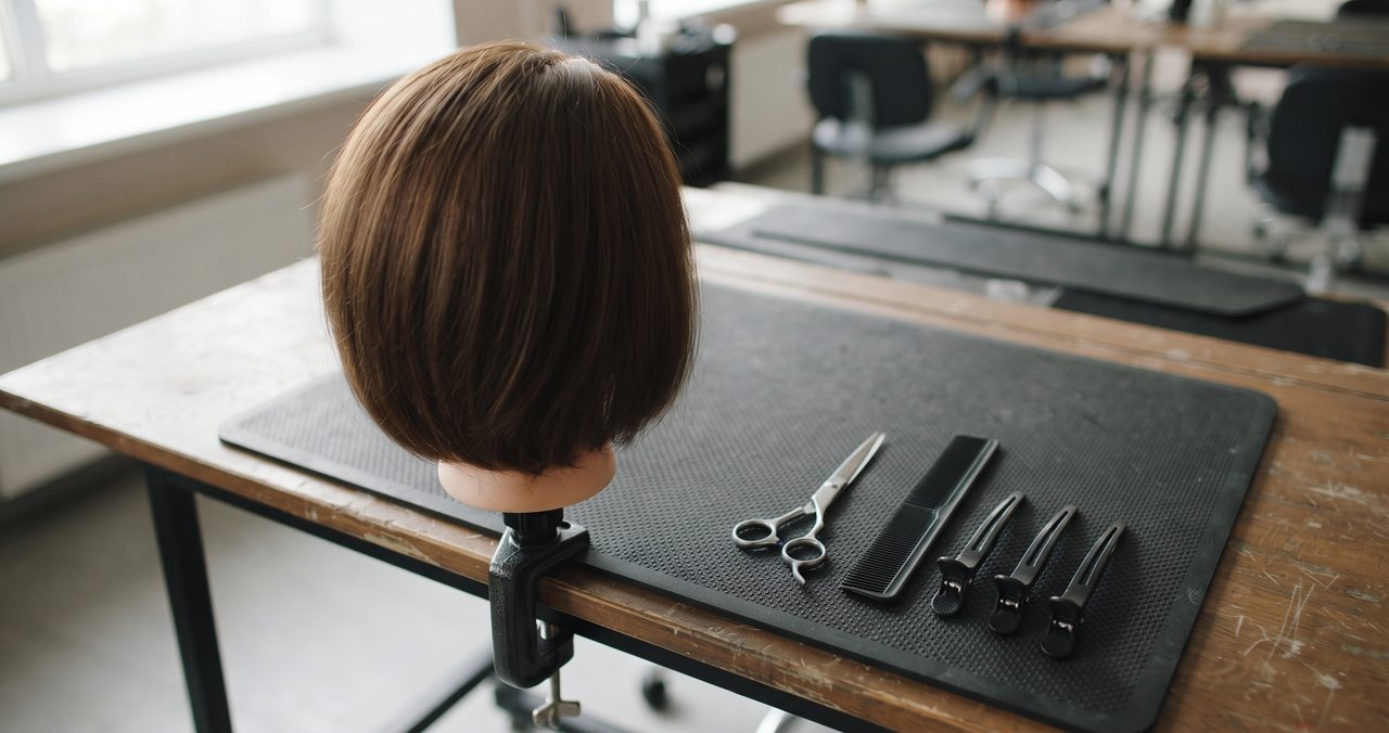 ウィッグ(練習用マネキンヘッド)とカット道具を並べた練習台の俯瞰、人物なし