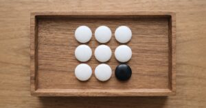 木製トレイに白い碁石9個と黒い碁石1個が並ぶ俯瞰物撮り、人物なし文字なし